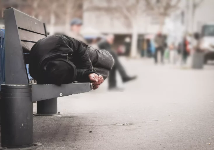 Symbolfoto von 5min.at: Obdachloser Mann liegt auf einer Parkbank.