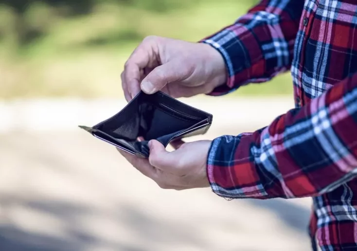 Symbolfoto von 5min.at: Mann zeigt eine leere Brieftasche in die Kamera.
