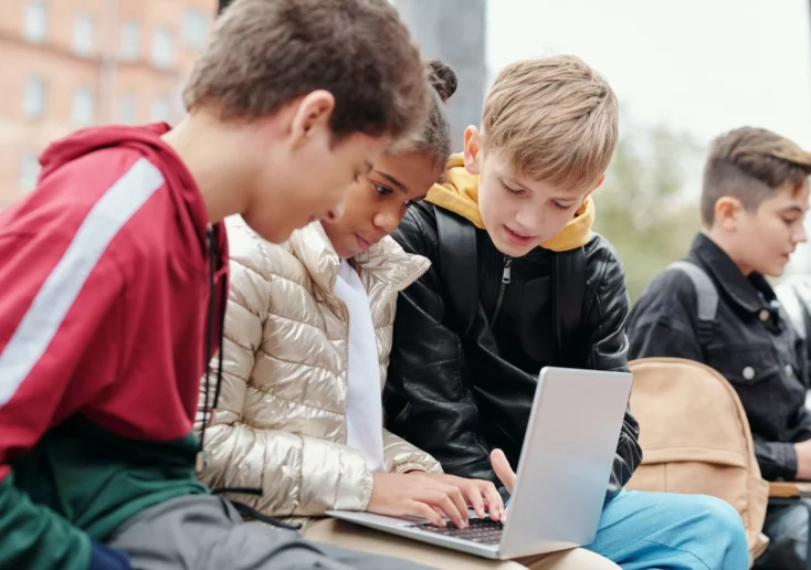 Ein Bild zeigt Kinder, die an einem Laptop sitzen.