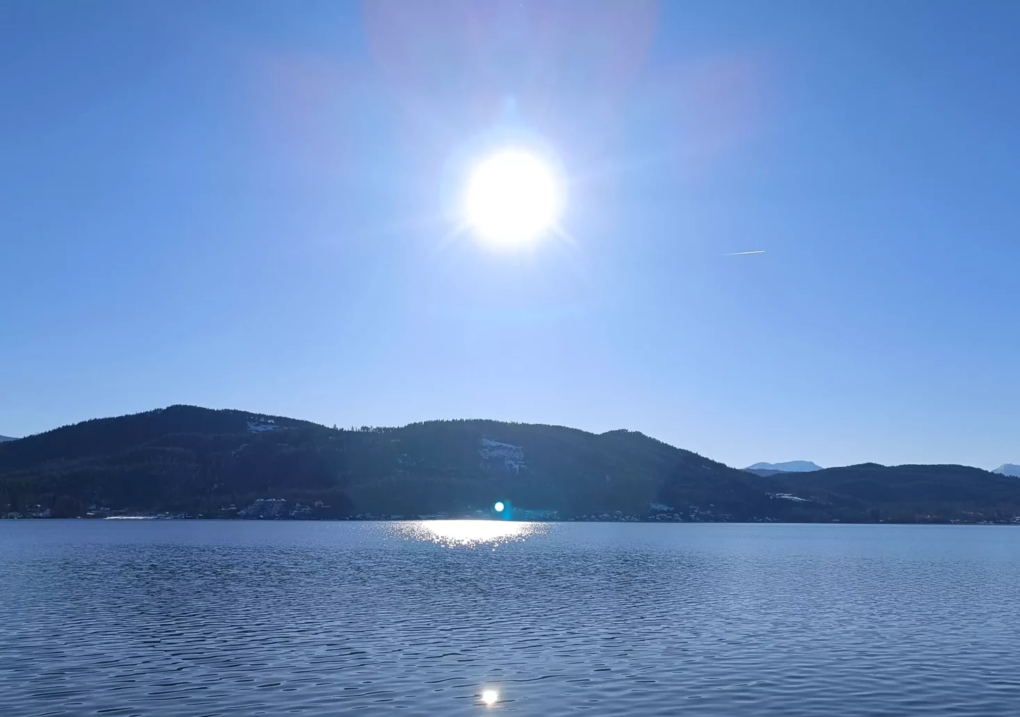 Ein Bild auf 5min.at zeigt das blaue Wasser des Wörthersees im Winter. Der Himmel ist strahlend blau, die Sonne scheint.