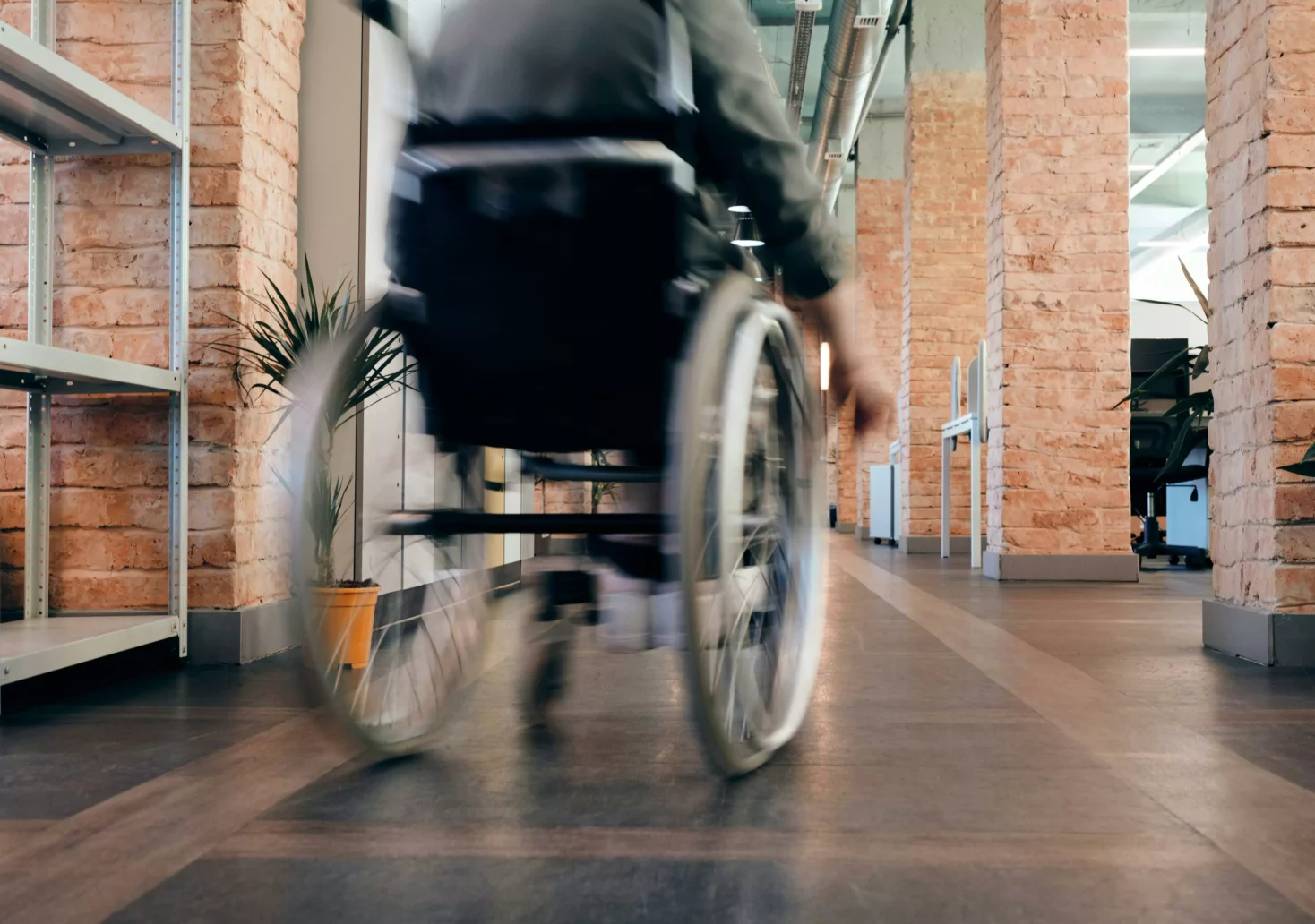 Ein Bild auf 5min.at zeigt eine Person in einem Rollstuhl, die durch einen Gang rollt.