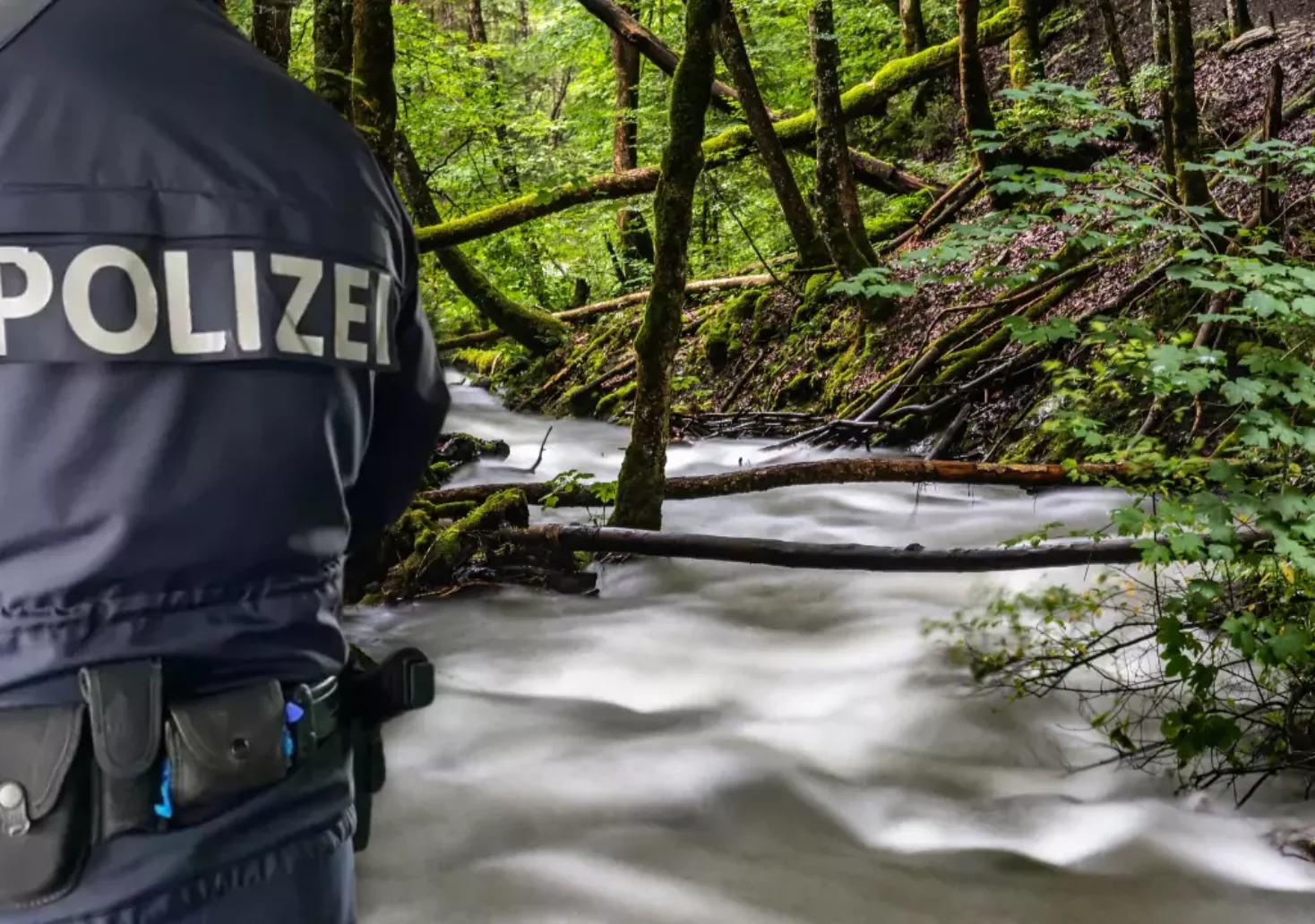 Bild auf 5min.at zeigt einen Polizisten im Vordergrund und im Hintergrund einen Bach im Wald.